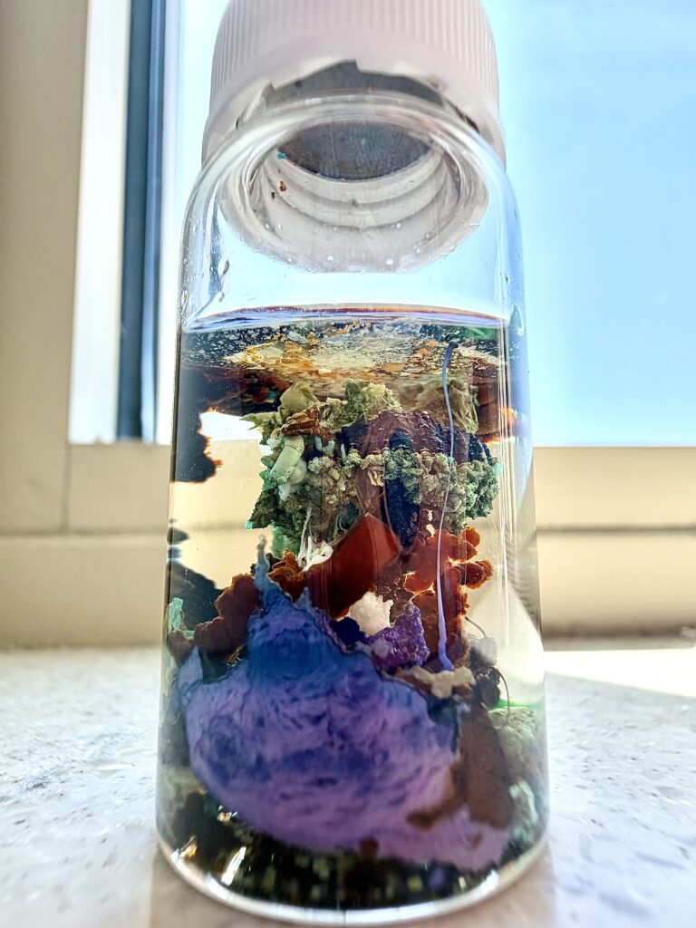 Small bottle with minerals forming complex structures.